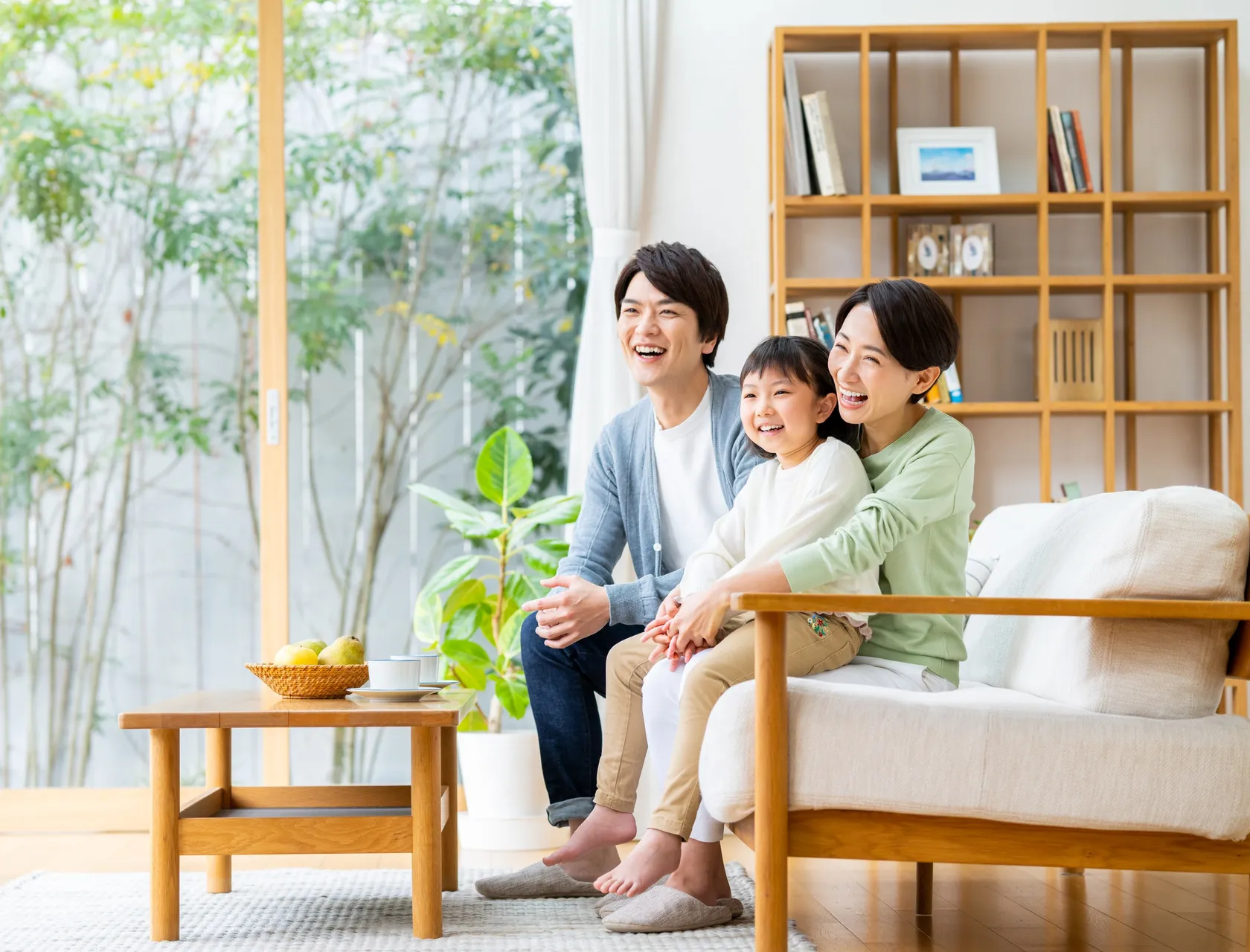 明るいリビングで笑う3人家族