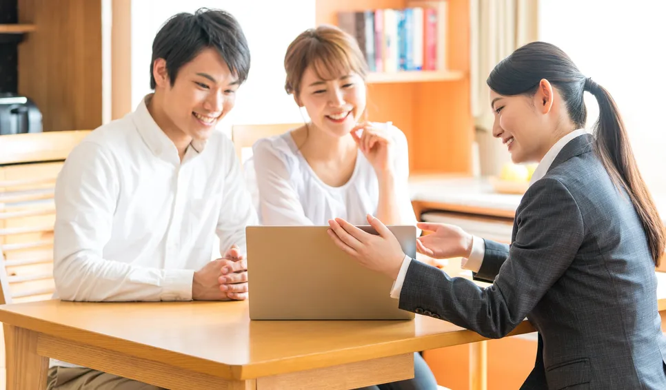 ノートパソコンを見ながら相談する夫婦とスタッフ