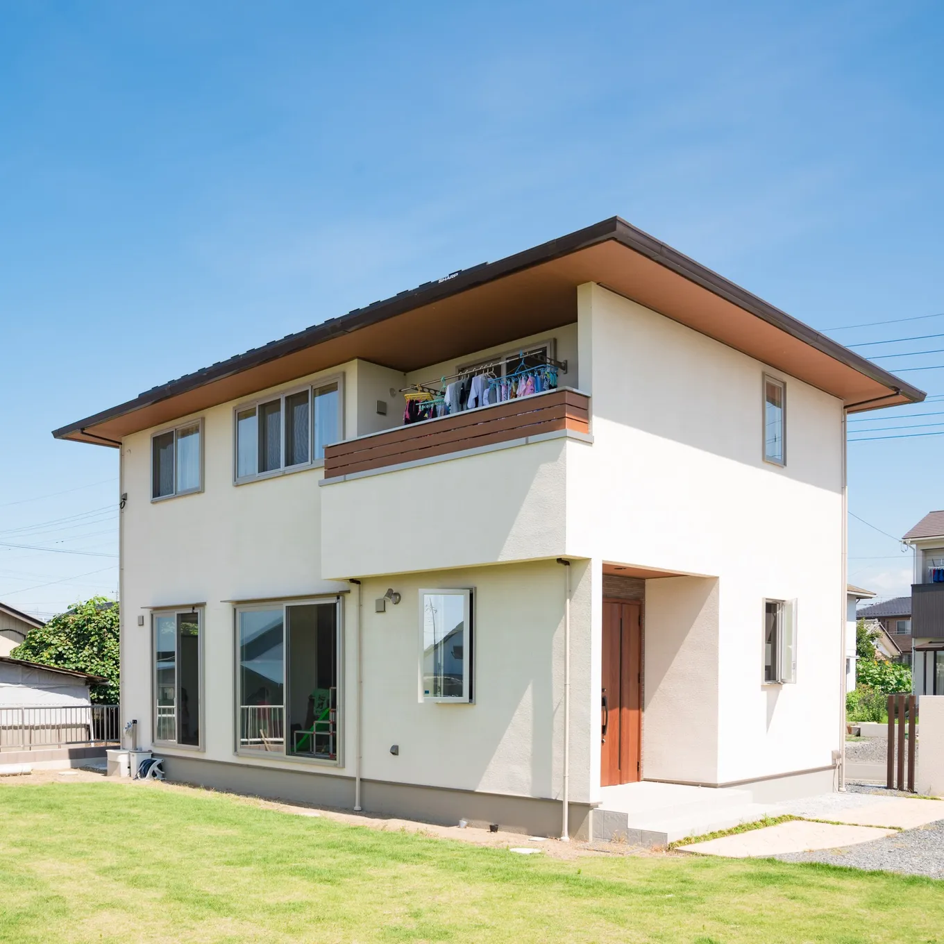 青空の下の白い外壁の2階建て住宅の外観