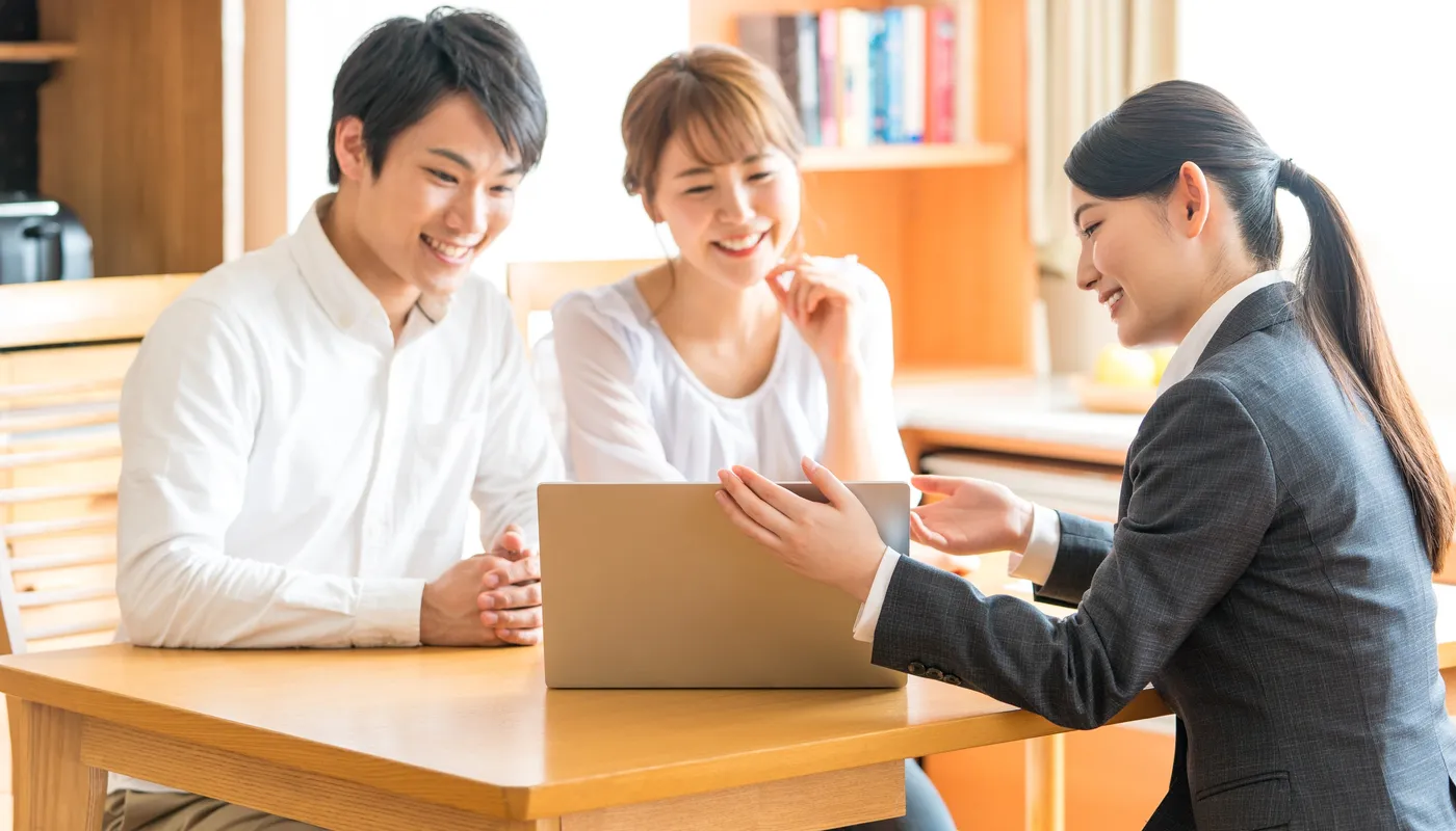 ノートパソコンを見ながら相談する夫婦とスタッフ