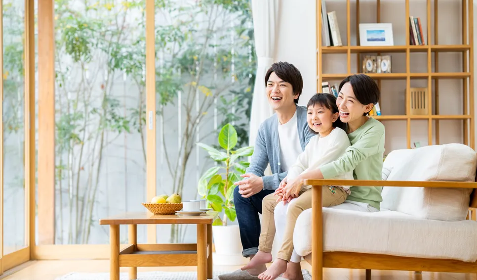 明るいリビングで笑う3人家族